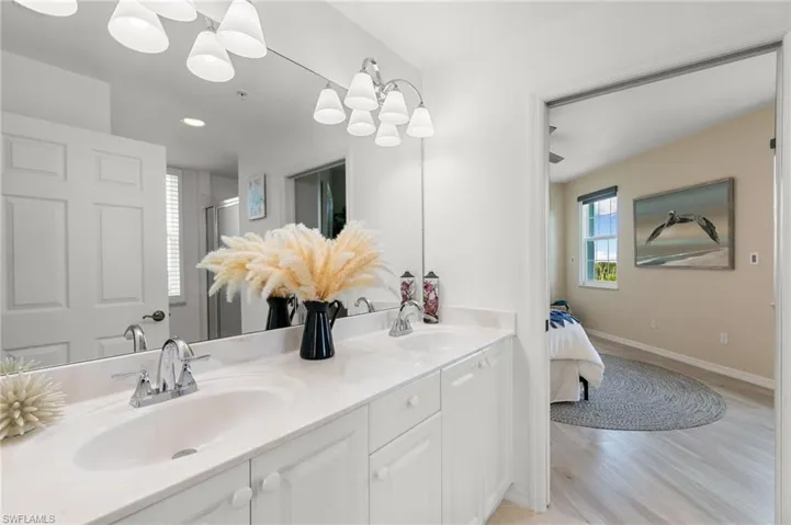 Bathroom with an inviting chandelier, vanity, a shower with shower door, and hardwood / wood-style flooring