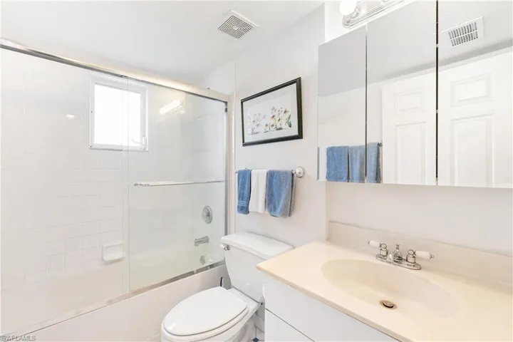 Full bathroom featuring vanity, bath / shower combo with glass door, and toilet