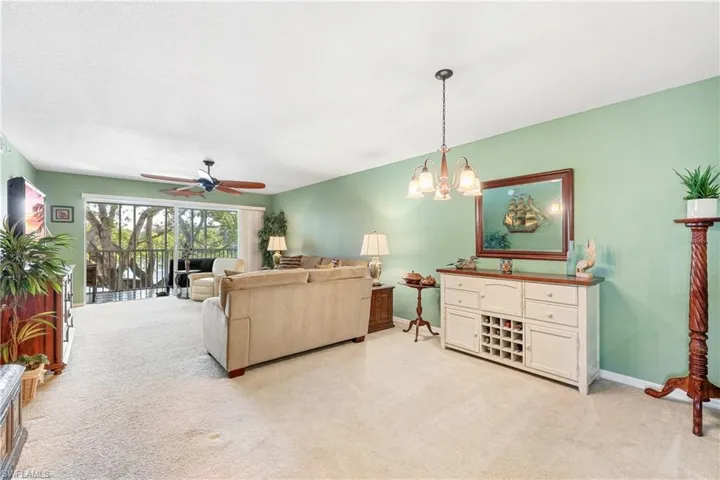 Carpeted living room featuring ceiling fan with notable chandelier