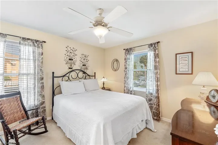 Bedroom featuring multiple windows, light colored carpet, and ceiling fan