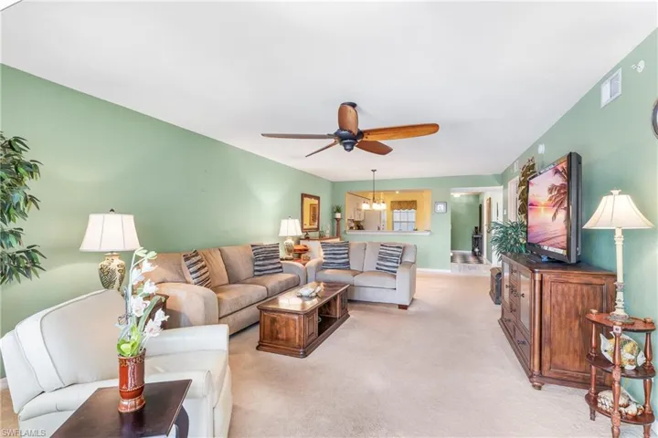 Living room featuring ceiling fan with notable chandelier