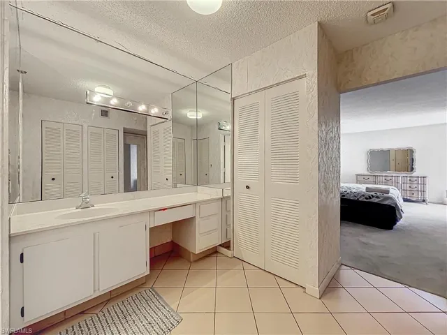 Bathroom featuring a textured ceiling, a closet, vanity, and tile patterned floors