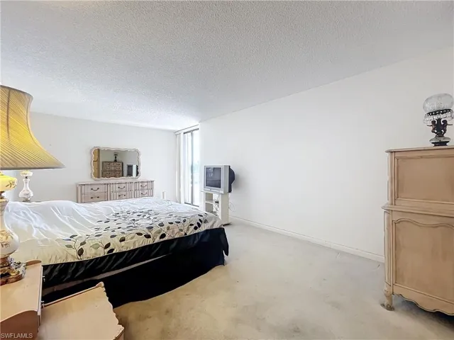 Carpeted bedroom with a textured ceiling and baseboards