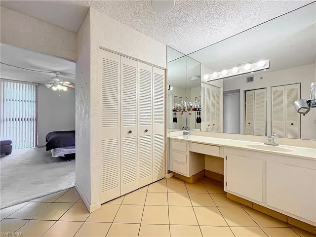 Bathroom featuring tile patterned floors, a closet, and a textured ceiling