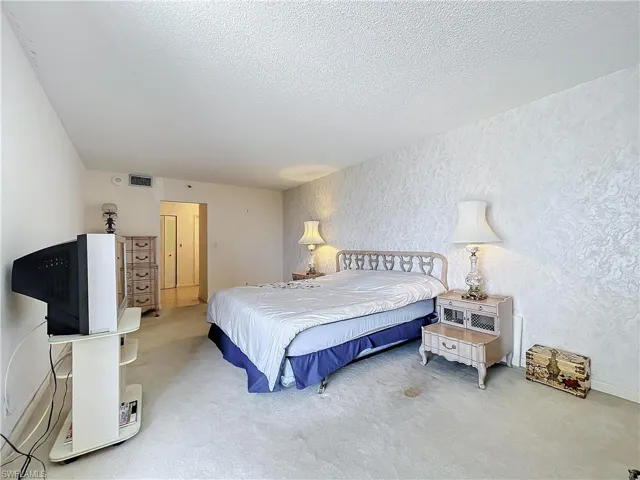 Bedroom featuring a textured ceiling, visible vents, and carpet floors