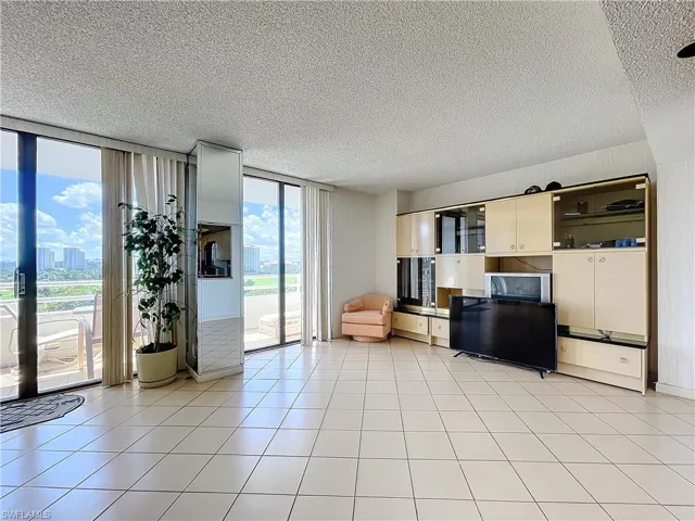Living area with expansive windows, light tile patterned floors, and a textured ceiling