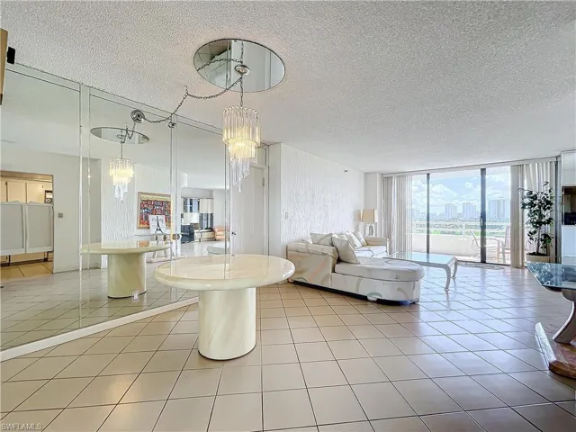 Living area with light tile patterned flooring, a textured ceiling, an inviting chandelier, and a wall of windows