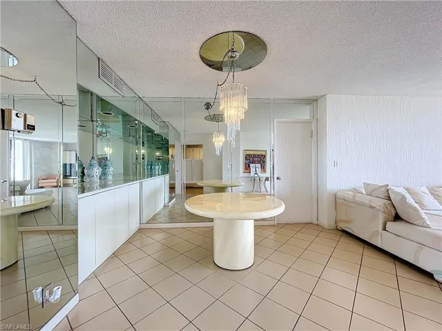 Dining room with visible vents, a notable chandelier, light tile patterned floors, and a textured ceiling