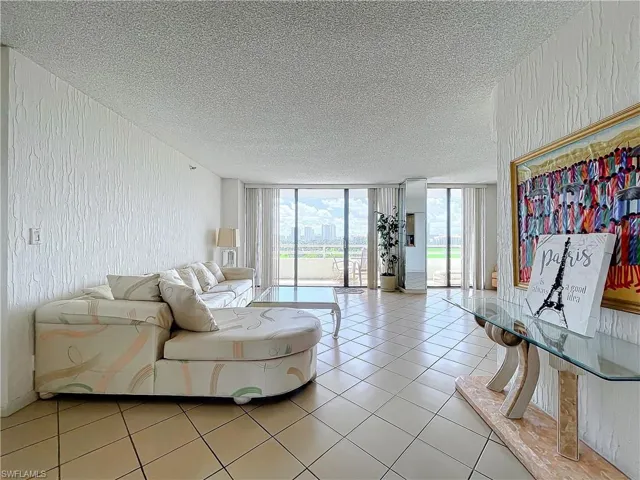 Living room with a textured ceiling, light tile patterned floors, and expansive windows