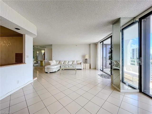 Living room featuring a textured ceiling, light tile patterned flooring, and expansive windows