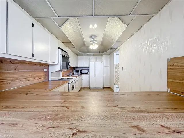 Kitchen featuring white appliances, light wood-style flooring, white cabinetry, and ceiling fan