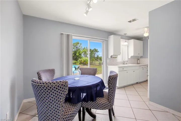 Casual dining area with direct outdoor access via a sliding glass door, featuring neutral tile flooring, light gray walls, and recessed lighting