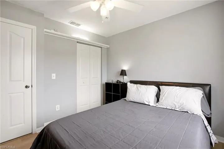 Bedroom featuring light gray walls, wood-finish flooring, a ceiling fan with integrated lighting, and a bi-fold closet