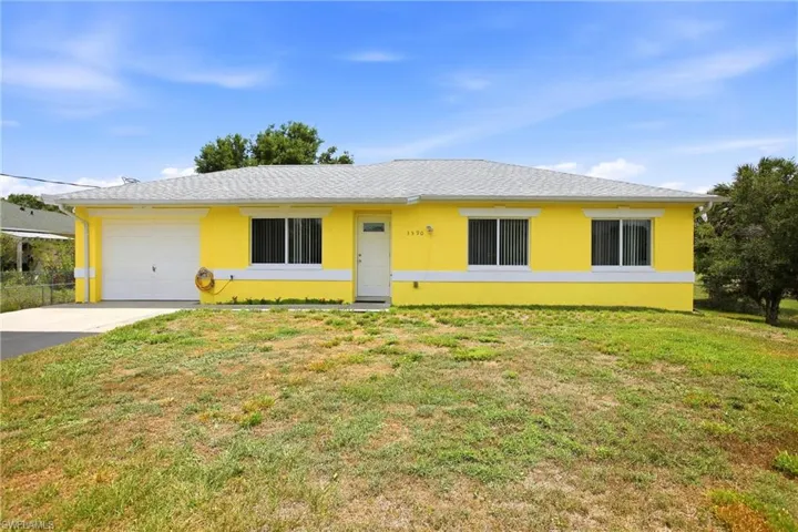 Single-story residence featuring a vibrant yellow exterior with white trim, a light grey shingle roof, and an attached single-car garage