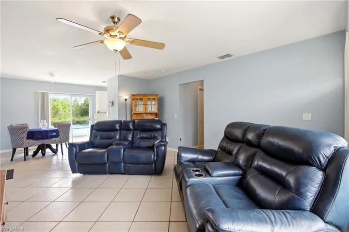 Open-concept living area featuring tile flooring, light blue wall tones, and a ceiling fan with integrated lighting