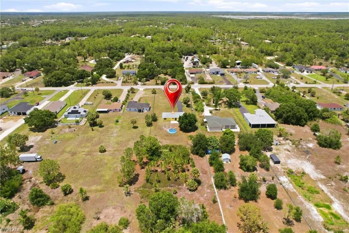 Aerial view showcasing the property with a central home, an in-ground pool, and surrounding green spaces