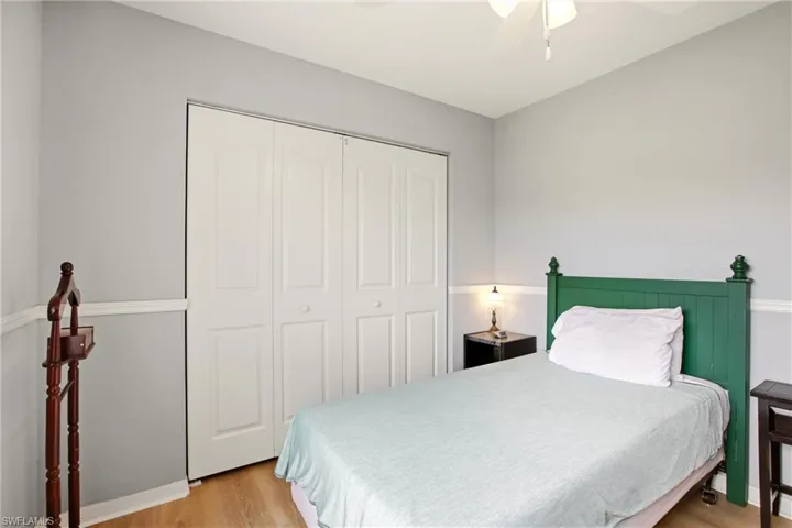 Room featuring a ceiling fan, light wood-finish flooring, bi-fold closet doors, and two-tone wall paint with a chair rail
