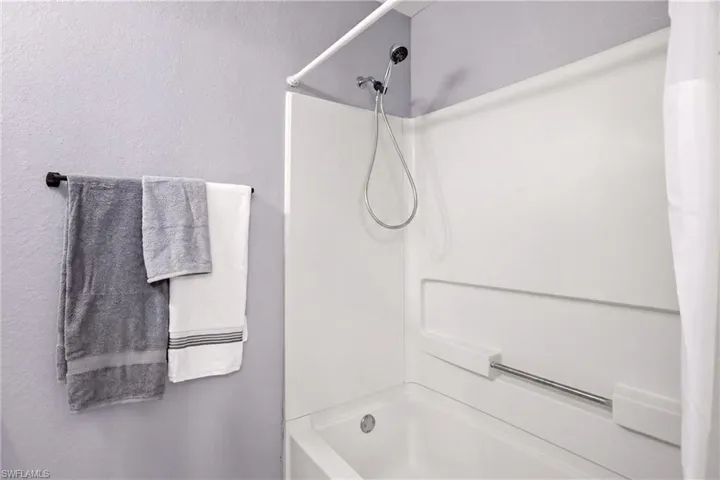 White bathtub and shower surround with a handheld showerhead
