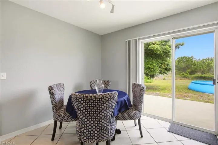 Sliding glass door opening to a concrete patio, featuring a light gray interior wall color, white baseboards, and neutral tile flooring