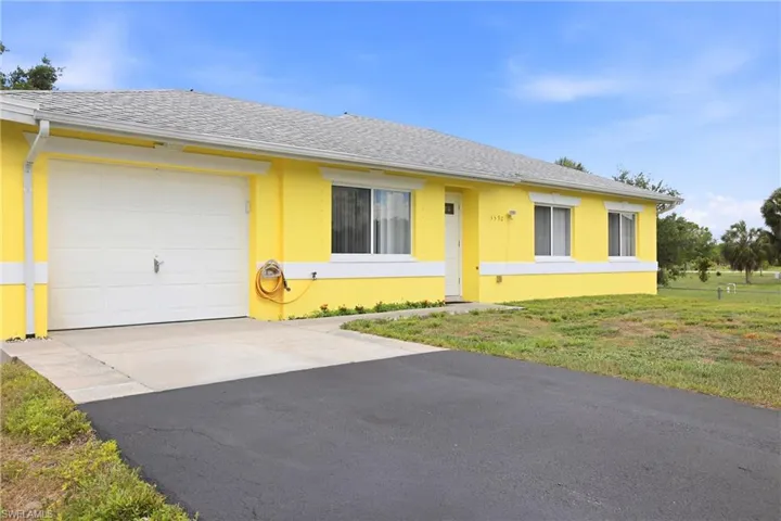 Single-story residence featuring a striking yellow exterior with white trim, a white garage door, and a gray shingle roof