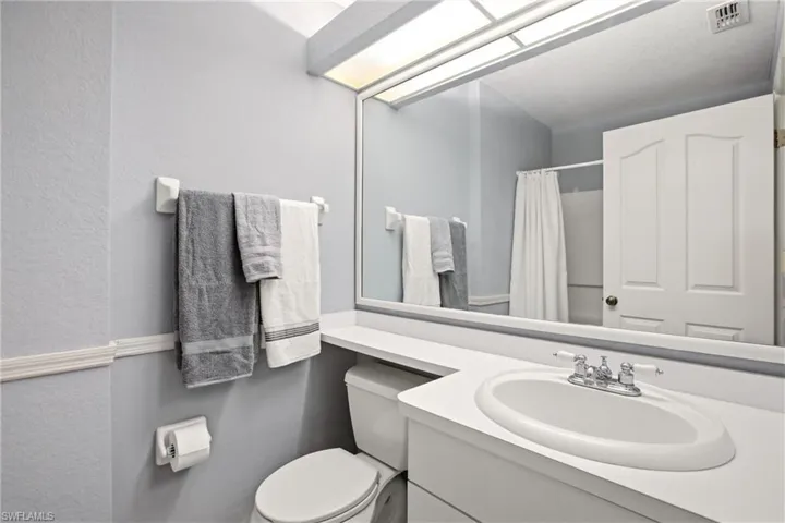 Bathroom featuring a single vanity with an integrated sink, chrome faucet, and a large wall-mounted mirror