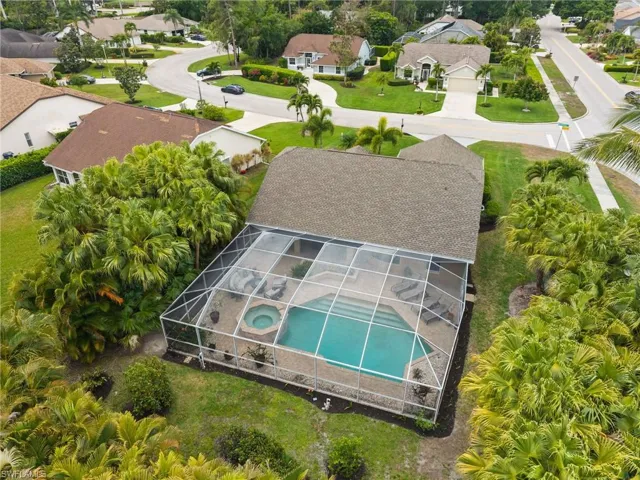 Aerial view featuring home, pool and spa and backyard with tropical trees and lush landscaping