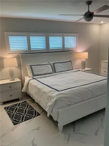 Bedroom with ceiling fan and light marble finish floors