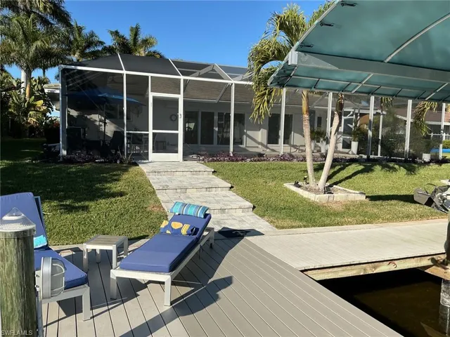 Back of property featuring glass enclosure, a lawn, a sunroom, and a deck
