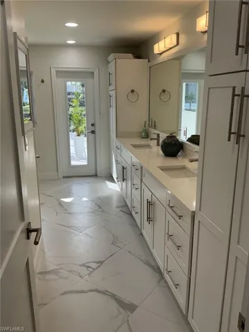 Bathroom with double vanity, light marble finish flooring, and recessed lighting