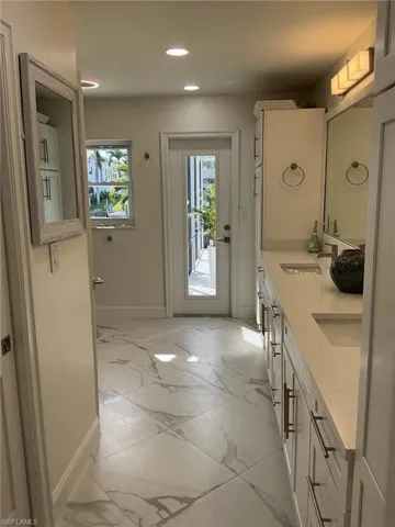 Bathroom with double vanity, recessed lighting, and light marble finish flooring