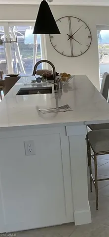 Kitchen view of a breakfast bar, a center island with sink, and white cabinets