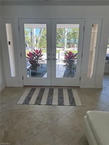 Doorway with french doors, tile patterned flooring, and healthy amount of natural light