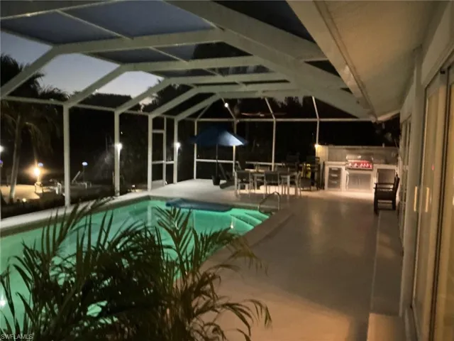 Pool at night featuring an outdoor pool and a sunroom