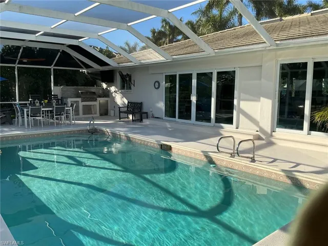Outdoor pool featuring a lanai, an outdoor kitchen / dining area, a patio, and a sunroom