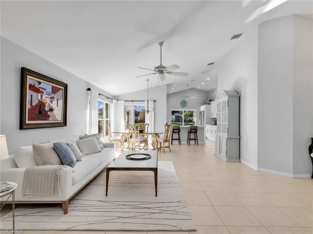 Living room with light tile patterned floors, a ceiling fan, and high vaulted ceiling