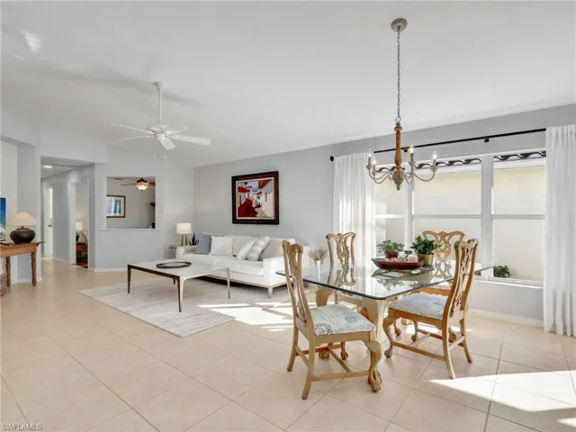 Dining area with lofted ceiling, light tile patterned floors, a chandelier, and ceiling fan