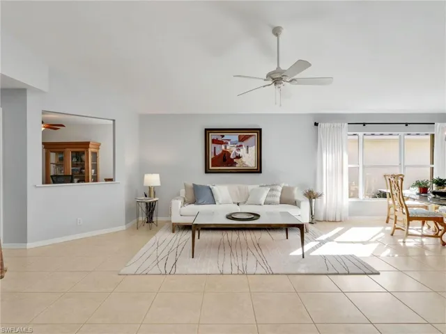 Living room with ceiling fan, light tile patterned floors, and lofted ceiling