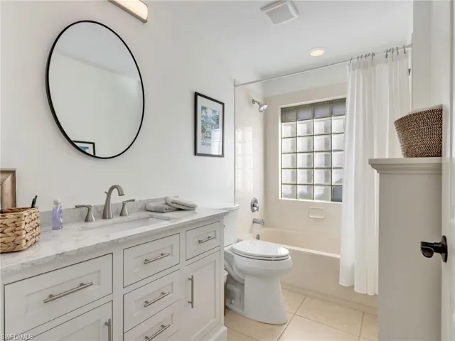 Bathroom featuring shower / bath combo with shower curtain, vanity, and light tile patterned floors