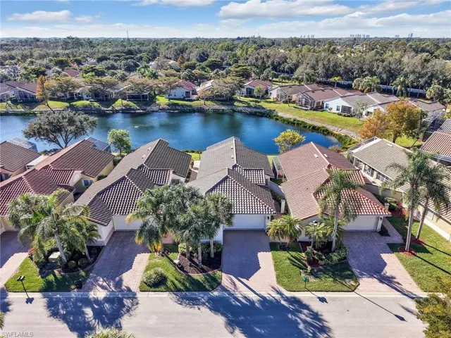 Aerial perspective of suburban area with a nearby body of water and a tree filled landscape