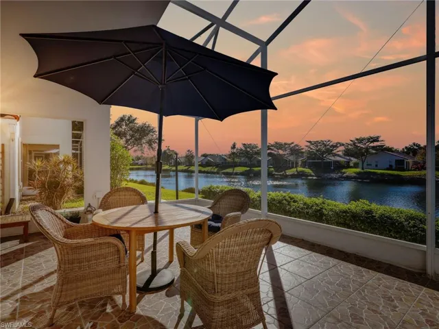 Sunroom with stone tile flooring, a water view, and a residential view