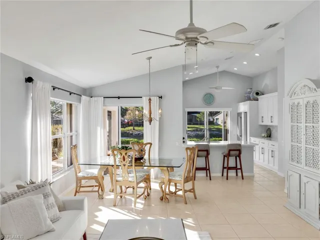 Dining area with light tile patterned floors, ceiling fan, a chandelier, high vaulted ceiling, and recessed lighting