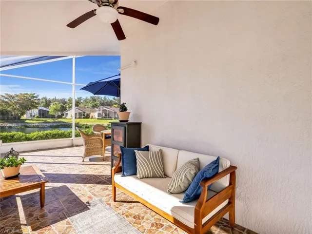 View of patio / terrace featuring a sunroom, ceiling fan, glass enclosure, a residential view, and a water view