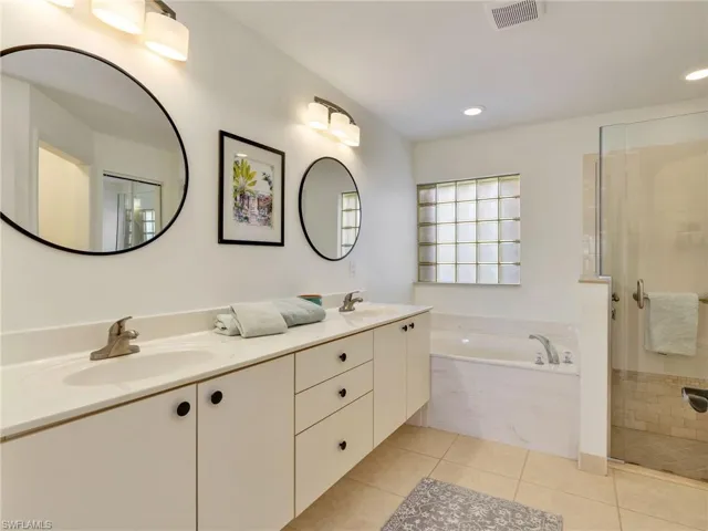 Full bathroom with double vanity, a garden tub, a shower stall, light tile patterned floors, and recessed lighting