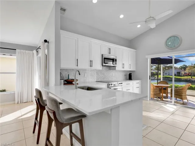 Kitchen with plenty of natural light, stainless steel appliances, a peninsula, a kitchen bar, and lofted ceiling