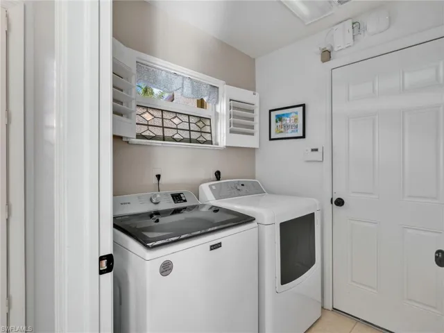 Laundry area with independent washer and dryer and light tile patterned flooring