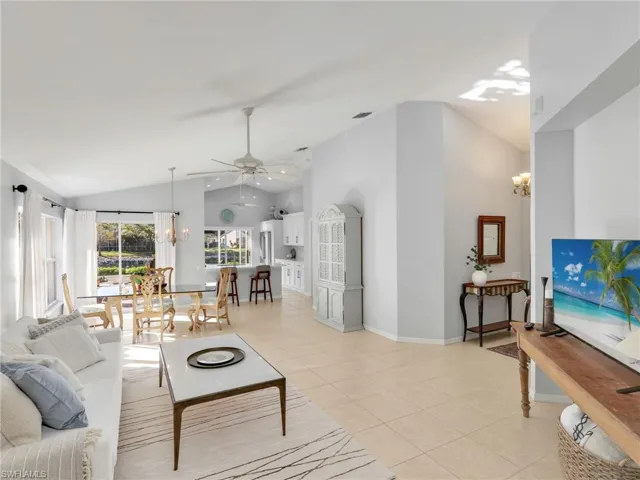 Living area featuring a chandelier, light tile patterned floors, a ceiling fan, and high vaulted ceiling