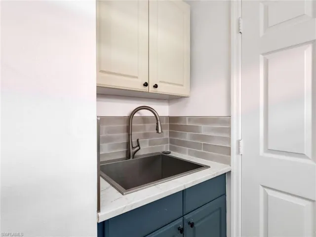Kitchen featuring decorative backsplash, light stone countertops, and blue cabinetry