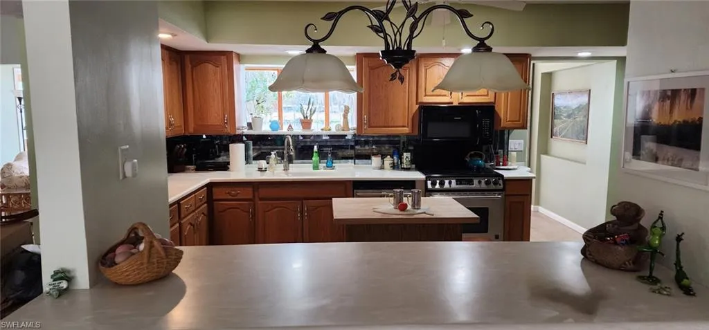 Kitchen featuring wood cabinets, stainless steel range,  microwave, and mirrored backsplash