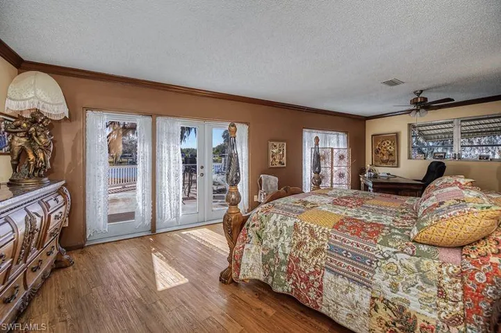 Master Bedroom with french doors, wood finished floors, crown molding, access to exterior, and a textured ceiling