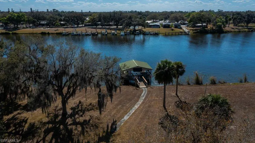 View of property location featuring a tree filled landscape and dock on Caloosahatchee River